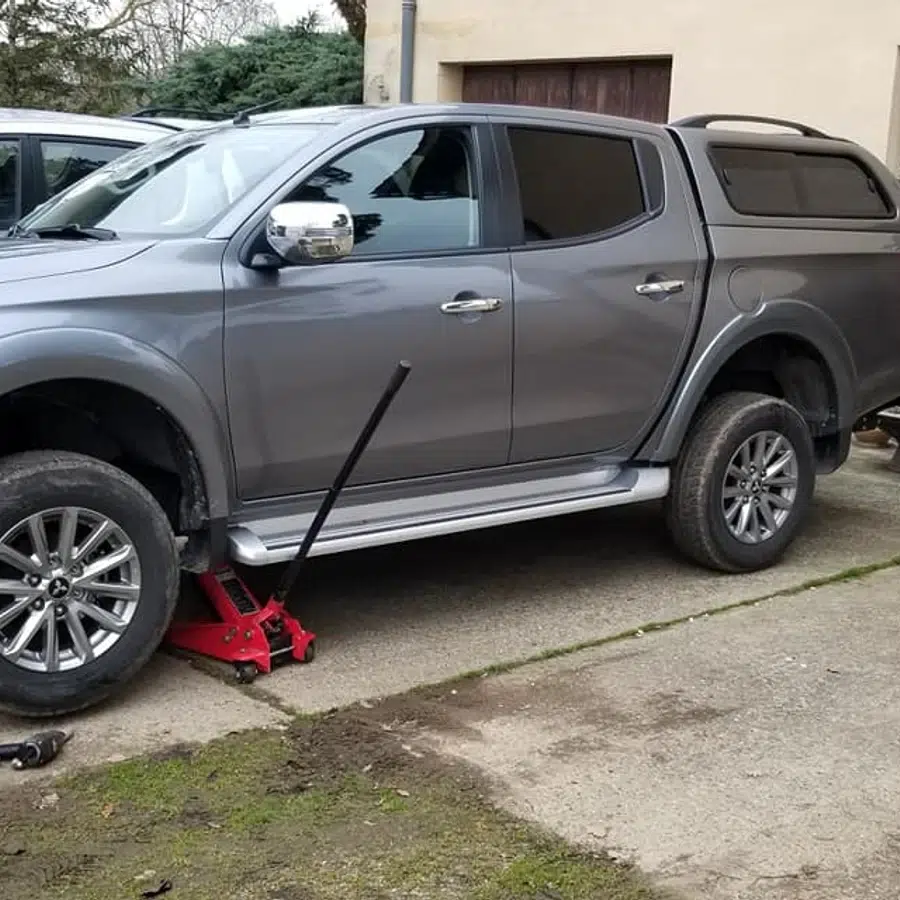 Camion gris sur cric avec roue manquante